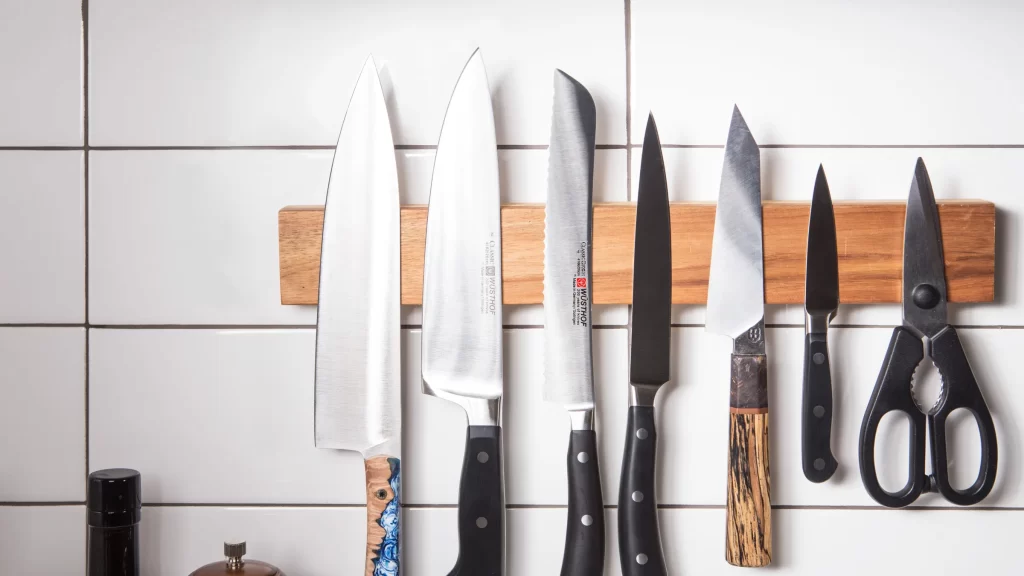 Small Kitchen Hacks: 25 Simple Tricks to Maximize Your Space and Efficiency 6 A magnetic knife strip attached to the kitchen wall with various knives hanging on it.