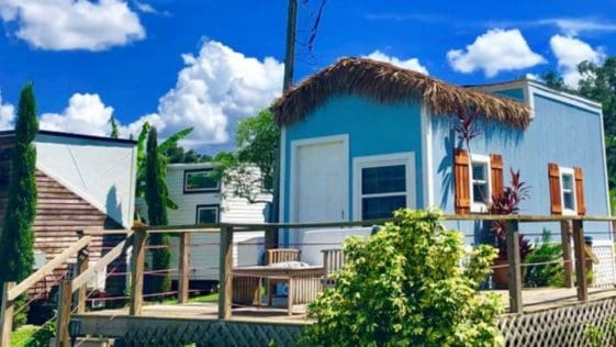 The Lake House is a custom tiny home with a gorgeous decor theme interior and a lovely thatched roof addition that feels like you are on the islands.