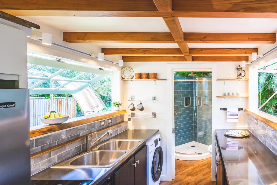 Maximizing Space in Style: A Modern Tiny House in Hawaii that Merges Nature and Design 5 An elongated kitchen window ties the interior to the outdoor deck, bar area, and landscape beyond.