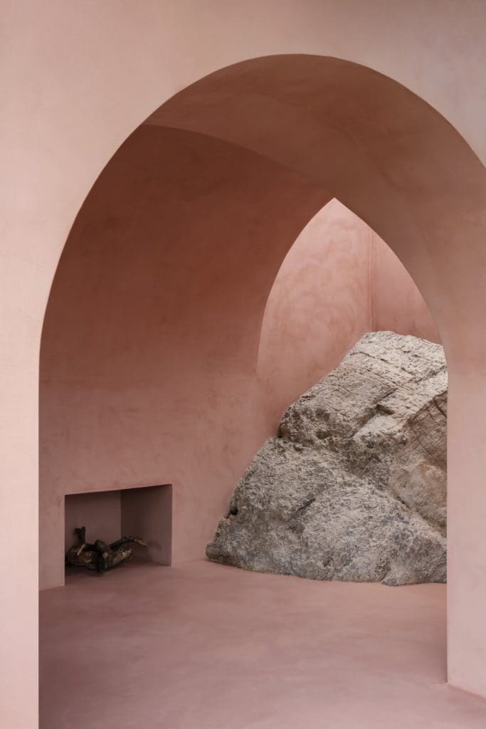 A Pair of Pink and Purple Tiny Houses Take Root in an Idyllic Olive Grove 4 a massive existing rock formation is embedded into the design anchoring one corner of the tiny home and tying it to nature